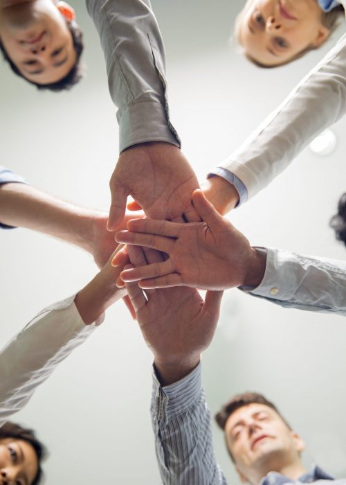 Below view of multiethnic business team stacking hands showing support, success and corporate spirit